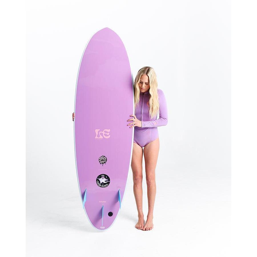 Woman in purple rash guard holding a purple surfboard, standing on white background.