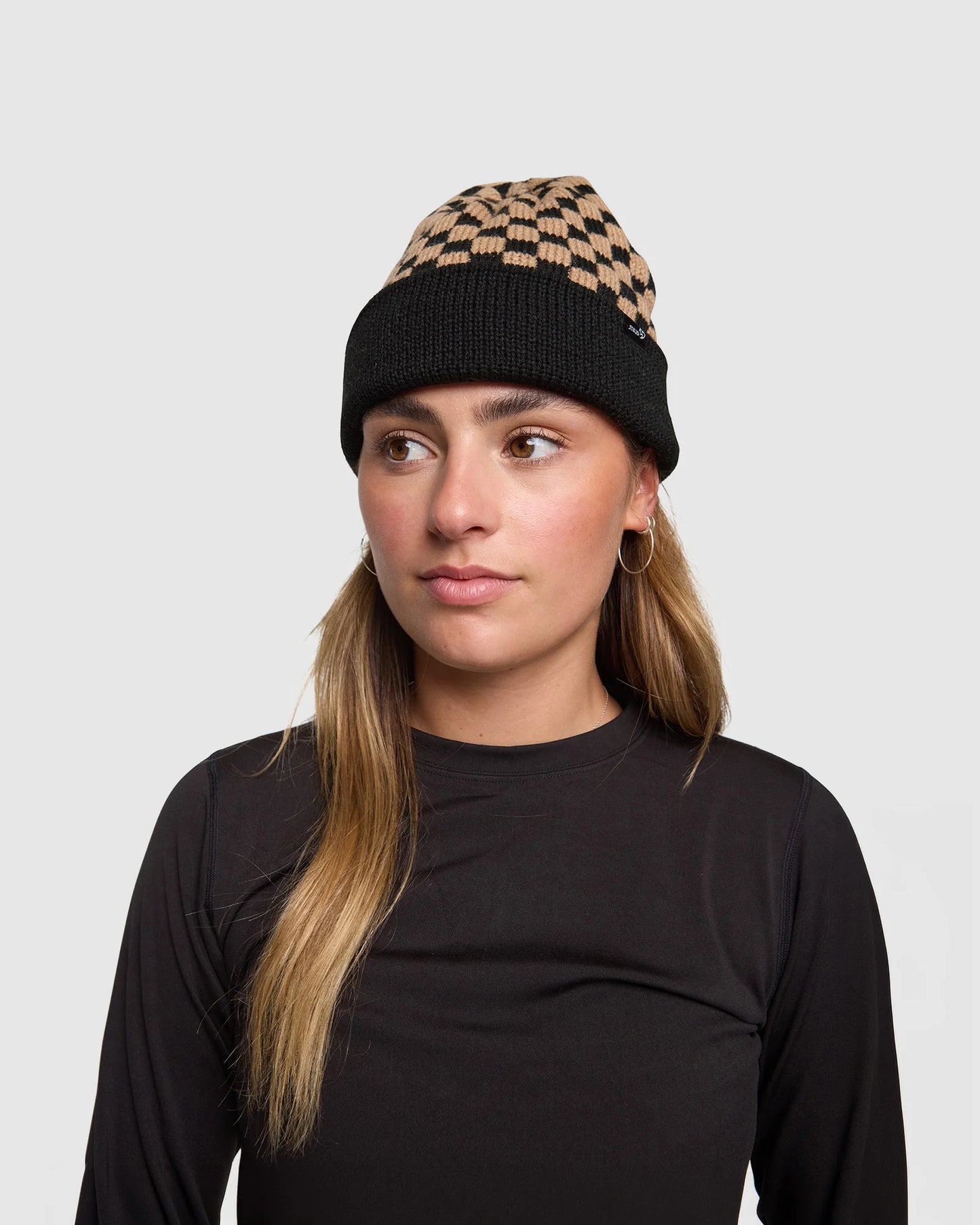 Woman wearing a black and patterned beanie on a plain background