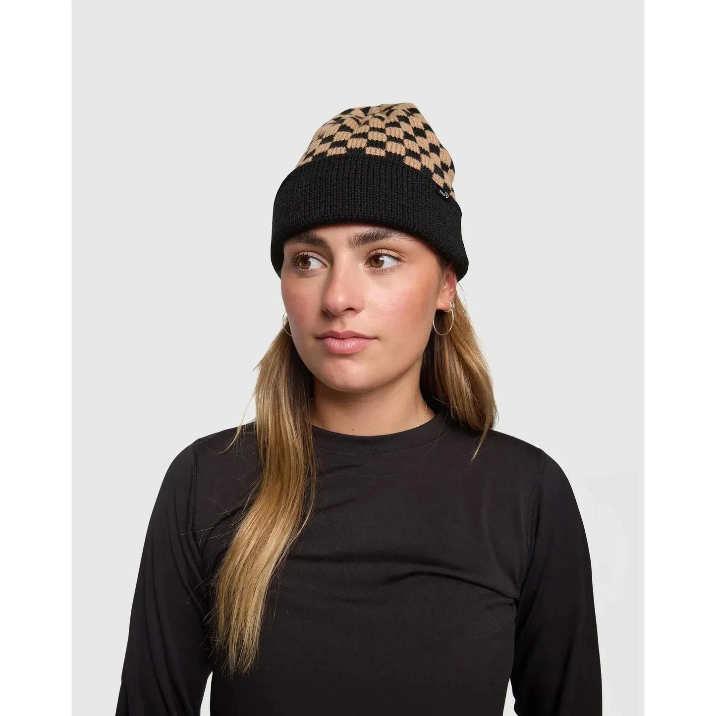 Woman wearing a black and patterned beanie on a plain background