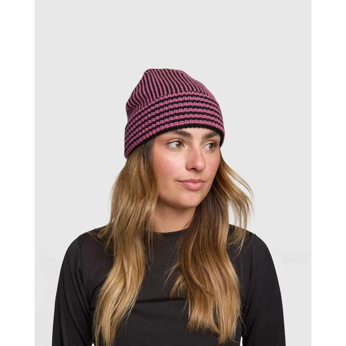 Rojo Vert Beanie Woman wearing a striped beanie against a plain background
