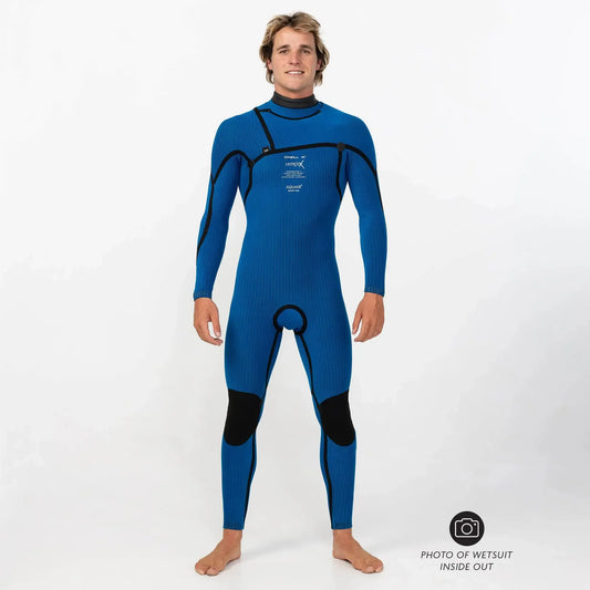 Man wearing blue full-length wetsuit turned inside out, standing barefoot on white background