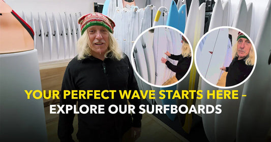 Man in surf shop with colorful surfboards, promotional text 'Explore Our Surfboards'.