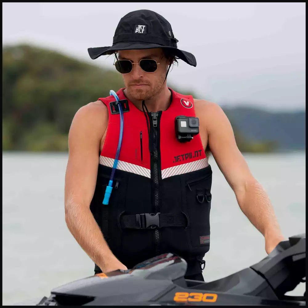 Man in Jetpilot life vest holding wakeboard by lake, Jetpilot logo, outdoor water sports gear