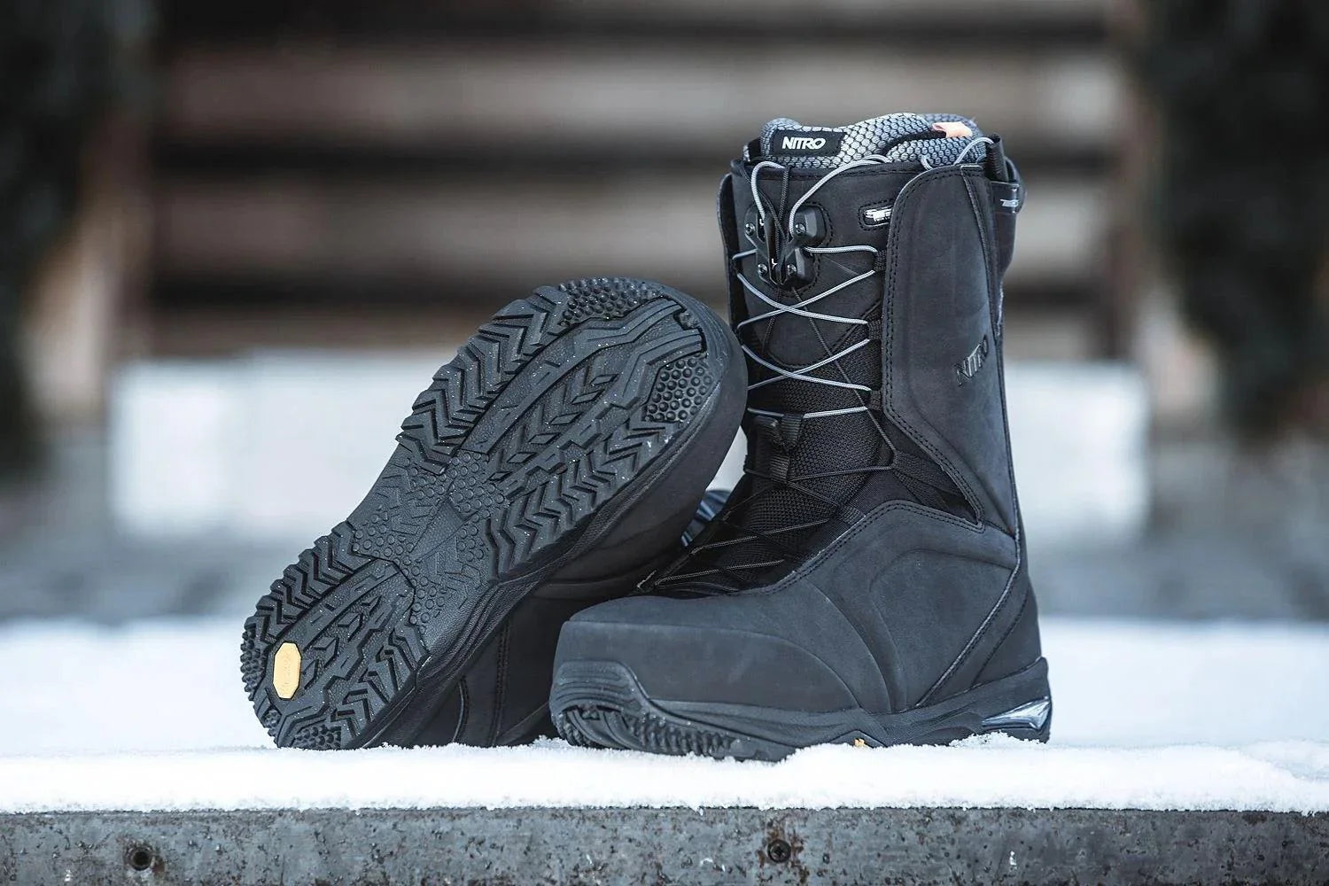 Black Nitro snowboard boots with rugged soles on snow, Wakeboard Snow Surf Essentials Australia