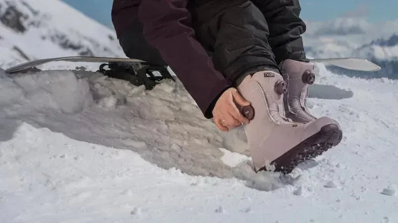 Person wearing light pink Tiara Boa snowboard boots in snowy mountain setting