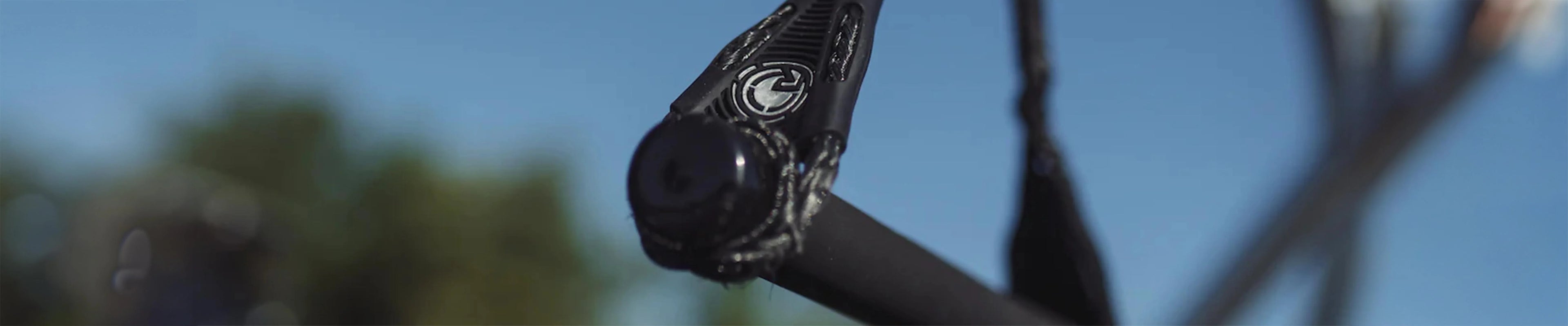Close-up of a black wakeboard tow handle with rope, outdoor blue sky background