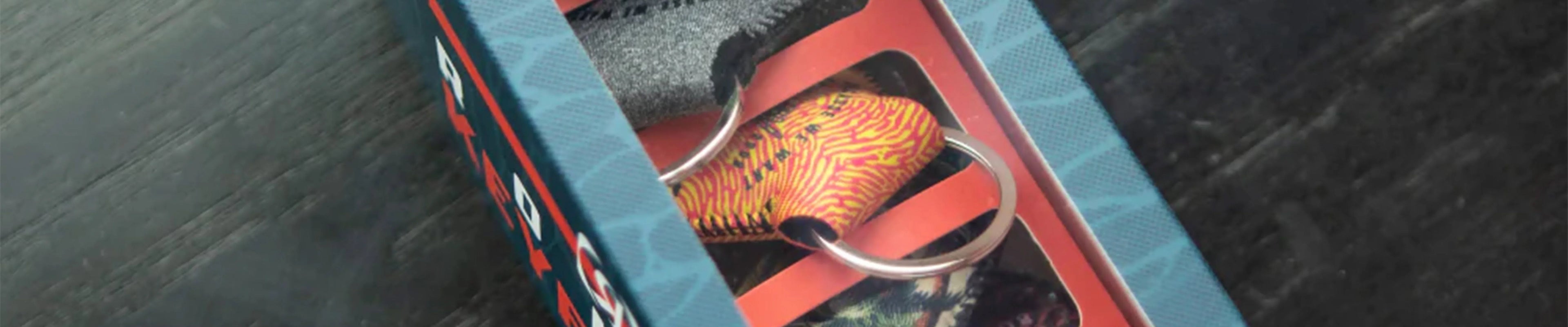 Wakeboard accessory box with colorful keyring, on dark wood surface, Boardstore Australia