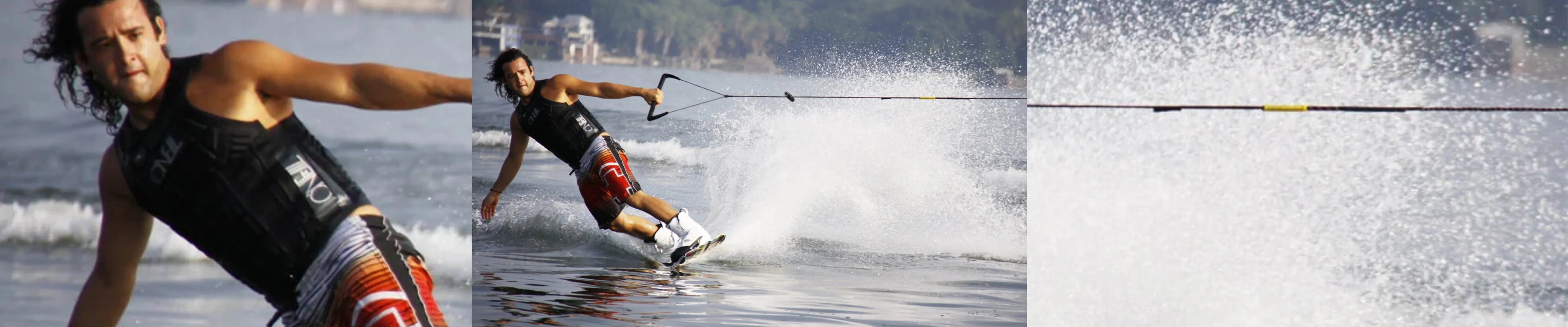 Man wakeboarding on water, wearing life vest and board shorts, with spray splashing behind