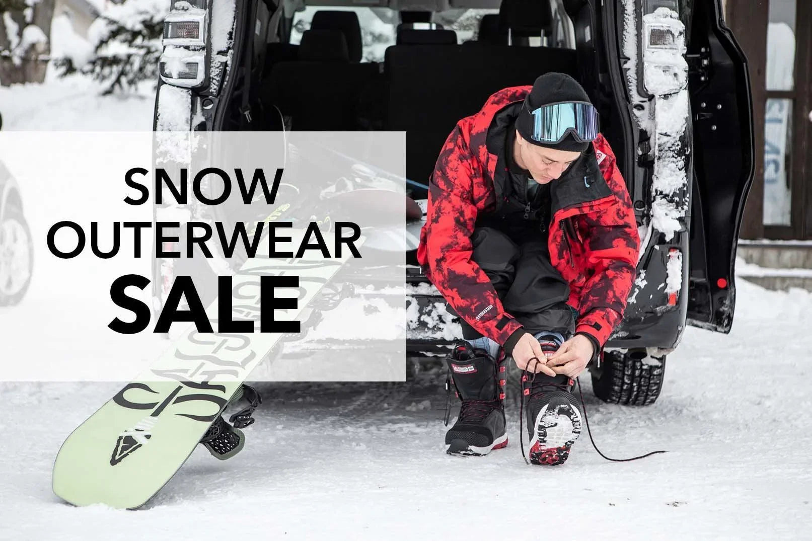 Snowboarder in red jacket tying boots by van, snowboard on snow, Snow Outerwear Sale.