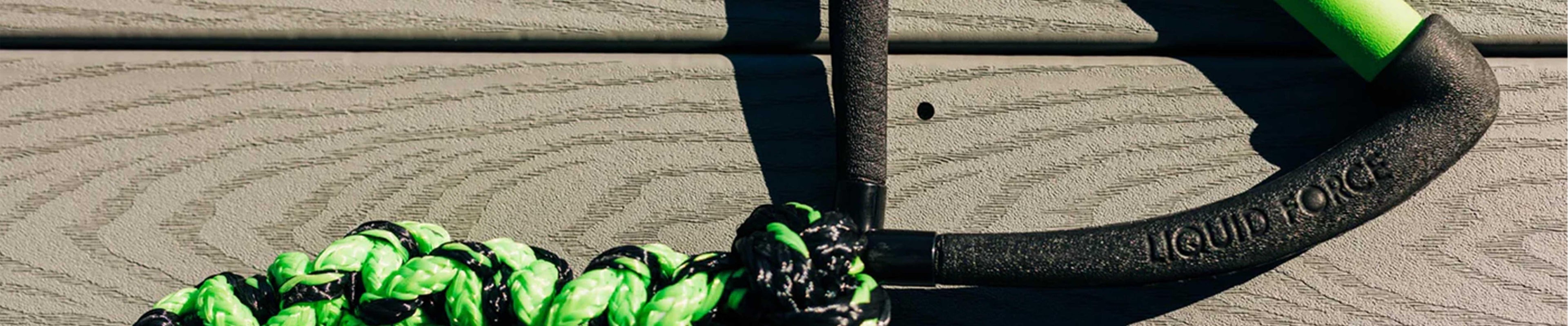 Wake surf rope with green and black handle on wood deck, wakeboard essentials Australia