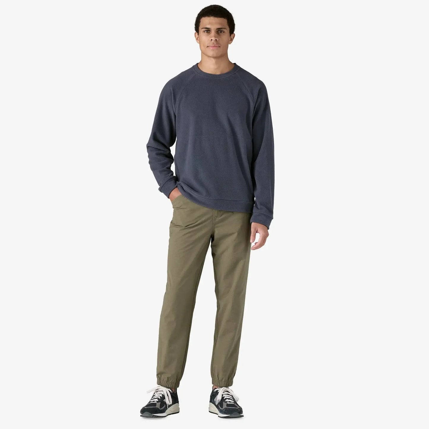 Man wearing a navy long-sleeve shirt and olive green pants on a white background