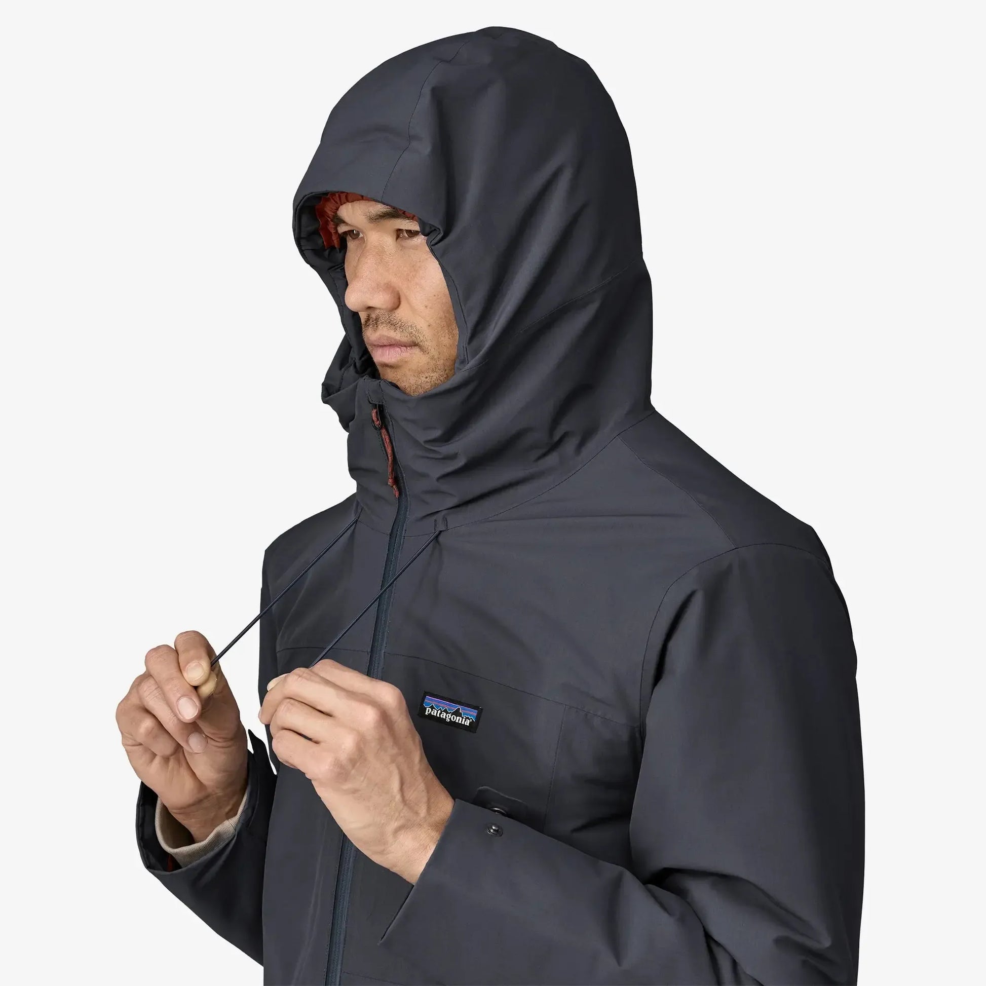 Person wearing a dark gray rain jacket with a hood on a white background