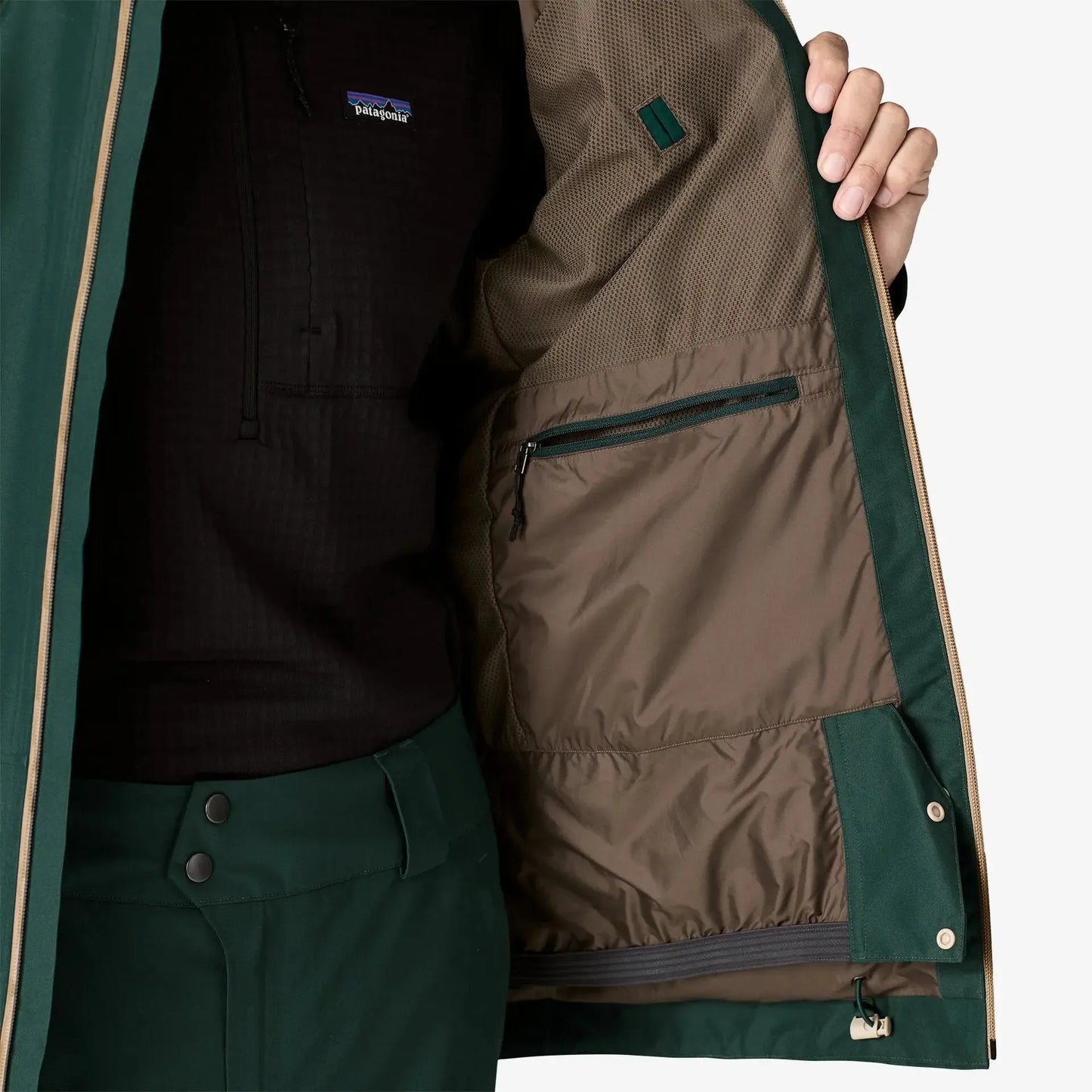 Close-up of a green jacket with a brown lining, featuring Patagonia branding.