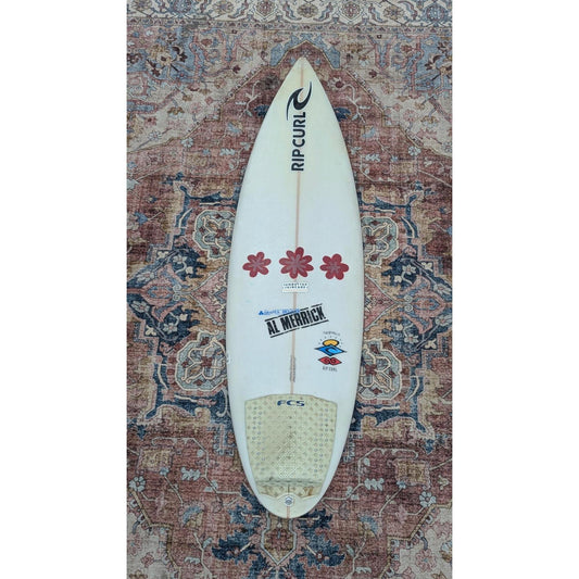 Surfboard with visible branding on a patterned rug