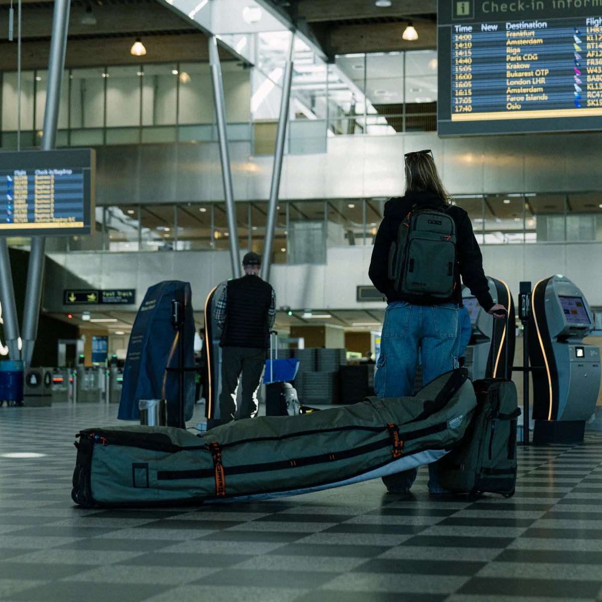 Person with a large green bag in an airport terminal with the FCS Day X Pack 24L on her back