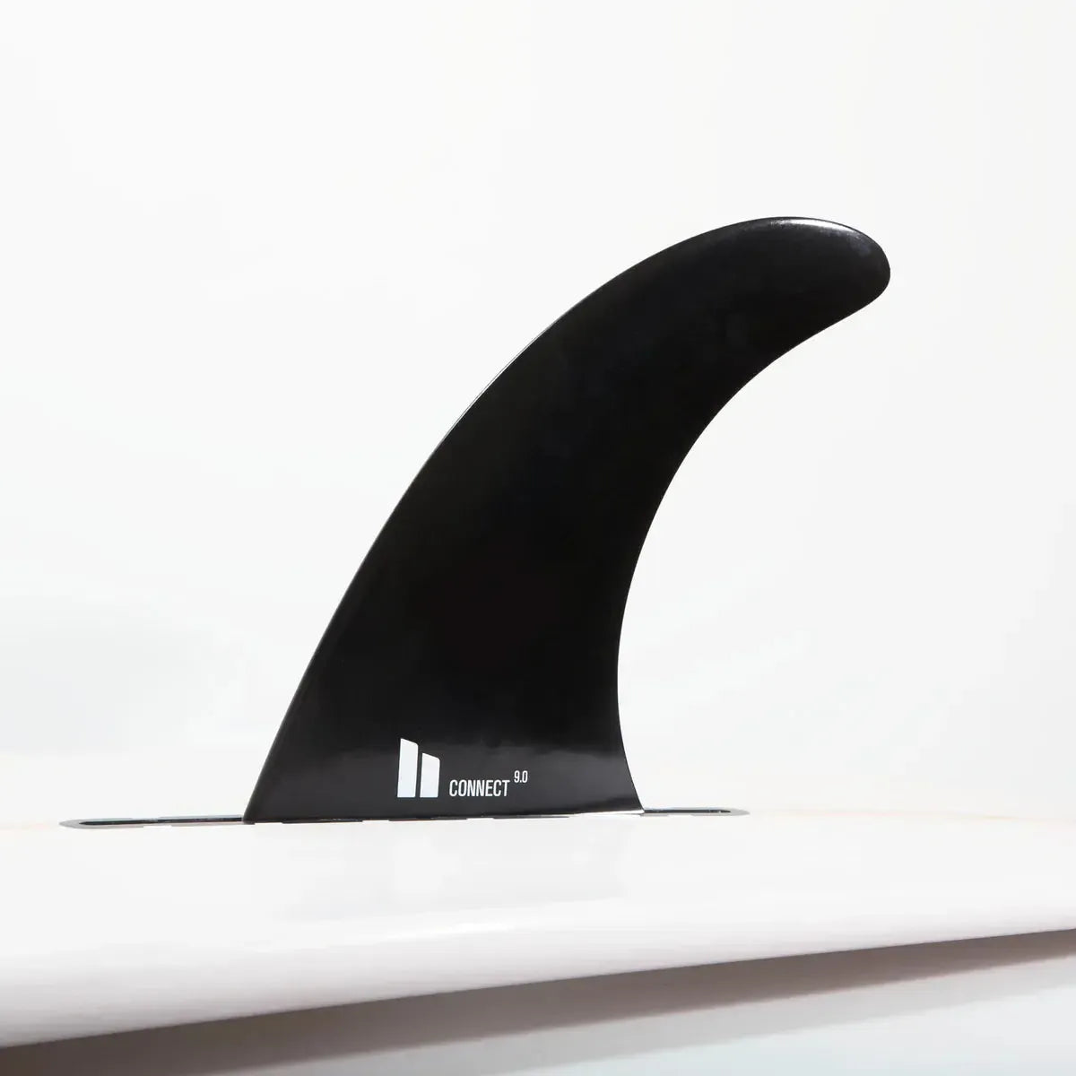 Black surfboard fin attached to white surfboard, minimalist background