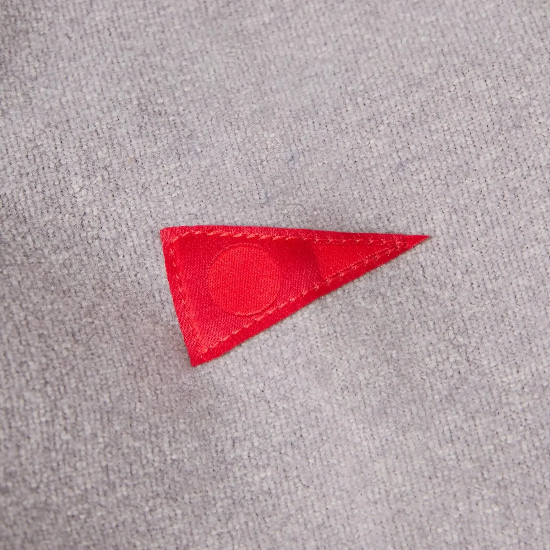 Red triangular patch on a gray fabric background
