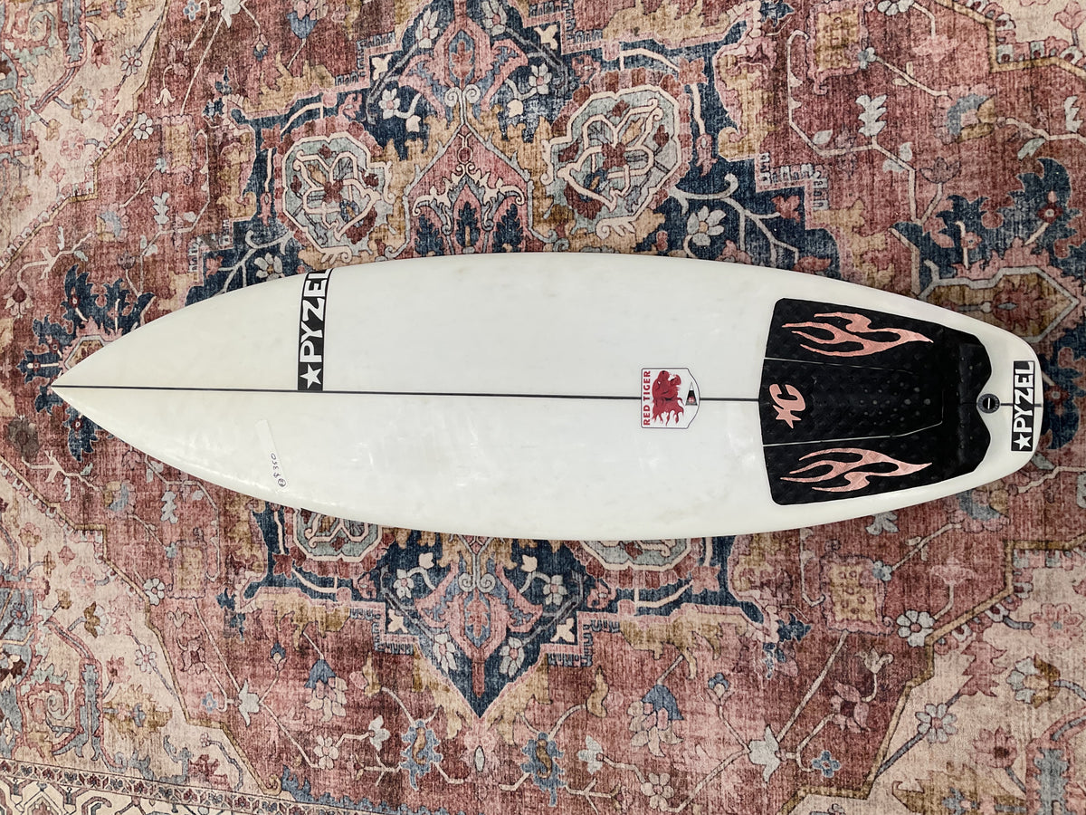 White Pyzel Red Tiger pre-loved surfboard deck with black flame tail pad on a patterned rug Welcome Board Store