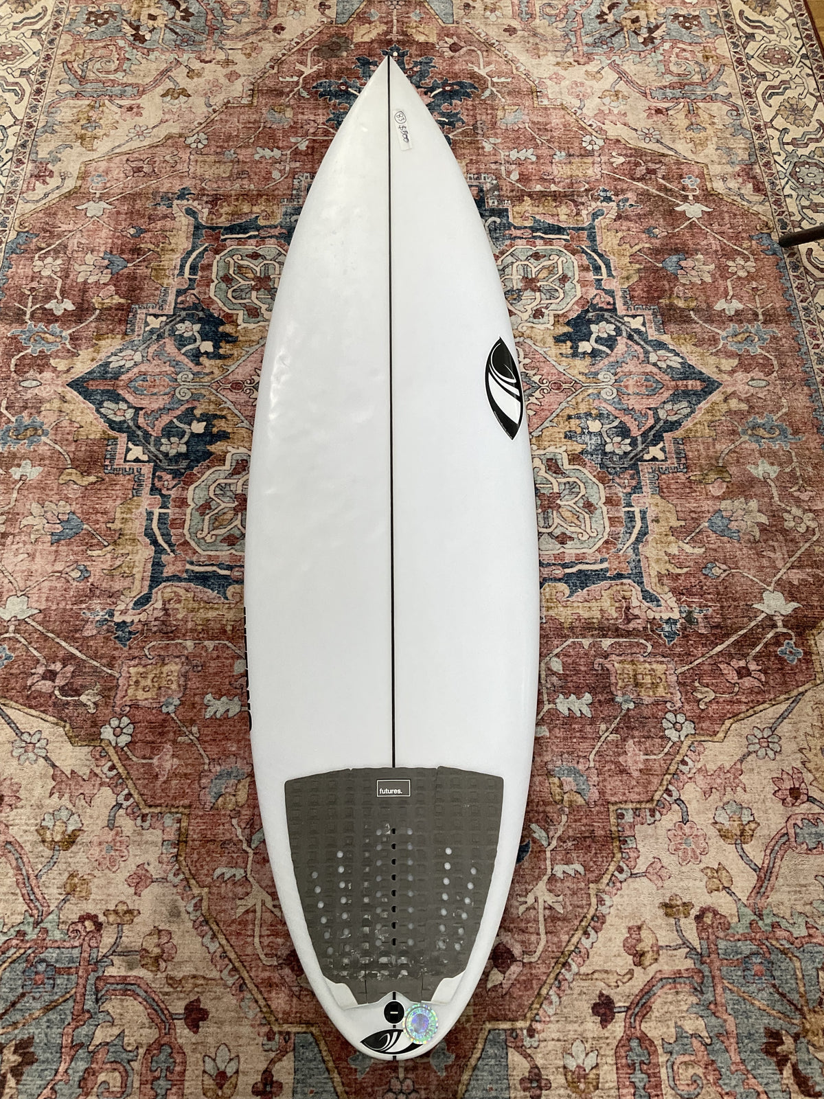 White Sharpeye Inferno 72 pre-loved surfboard deck with grey Futures tail pad on a patterned rug Welcome Board Store