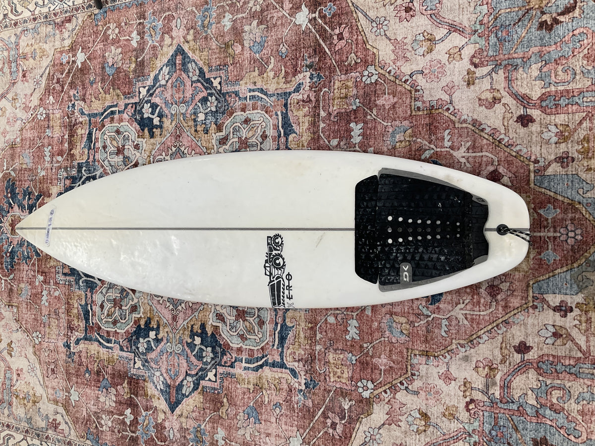 White JS Industries Xero pre-loved surfboard deck with black tail pad on a patterned rug Welcome Board Store