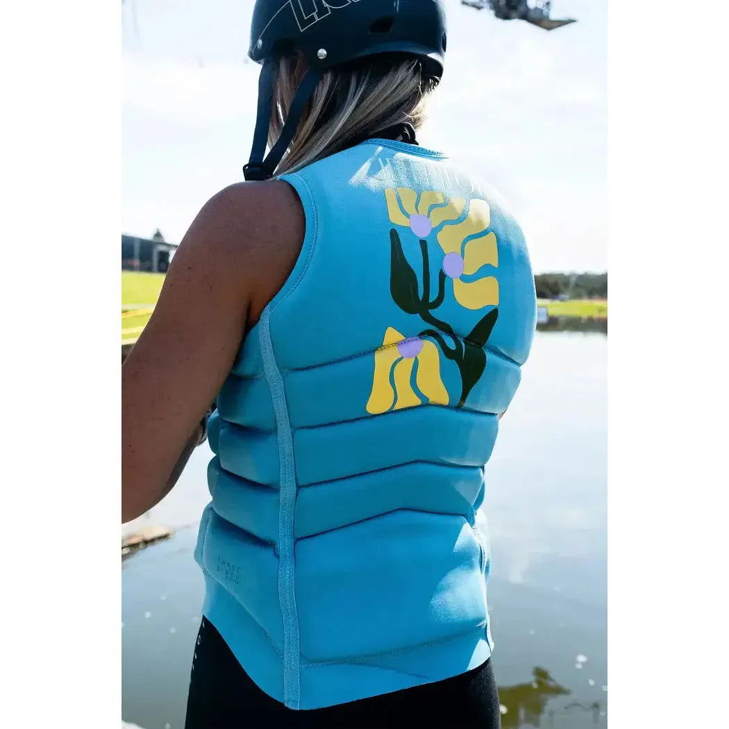 Woman wearing a blue Jetpilot life jacket with floral print by the water for wakeboarding