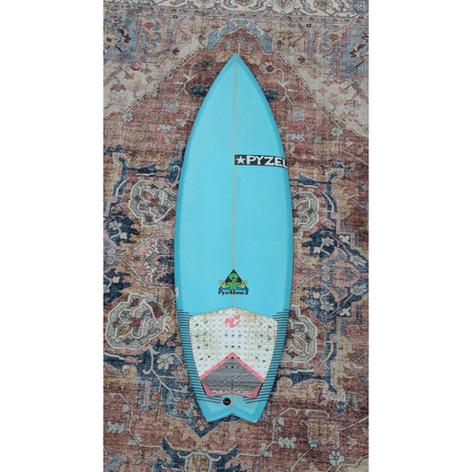 Blue surfboard with a logo on a patterned rug