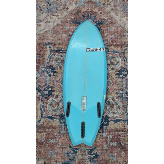Blue surfboard with 'Pyzel' branding on a patterned rug