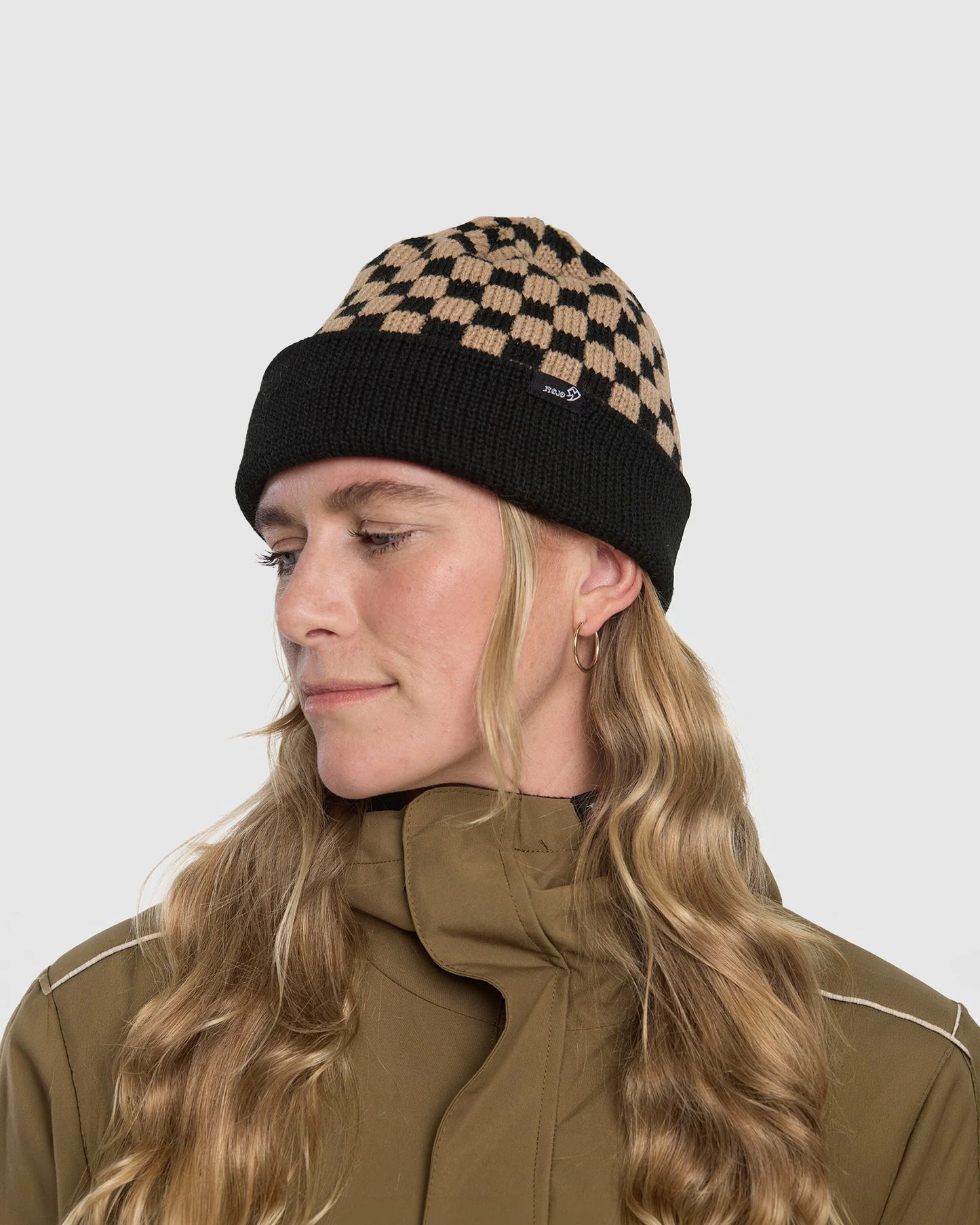 Person wearing a checkered beanie and brown jacket on a white background
