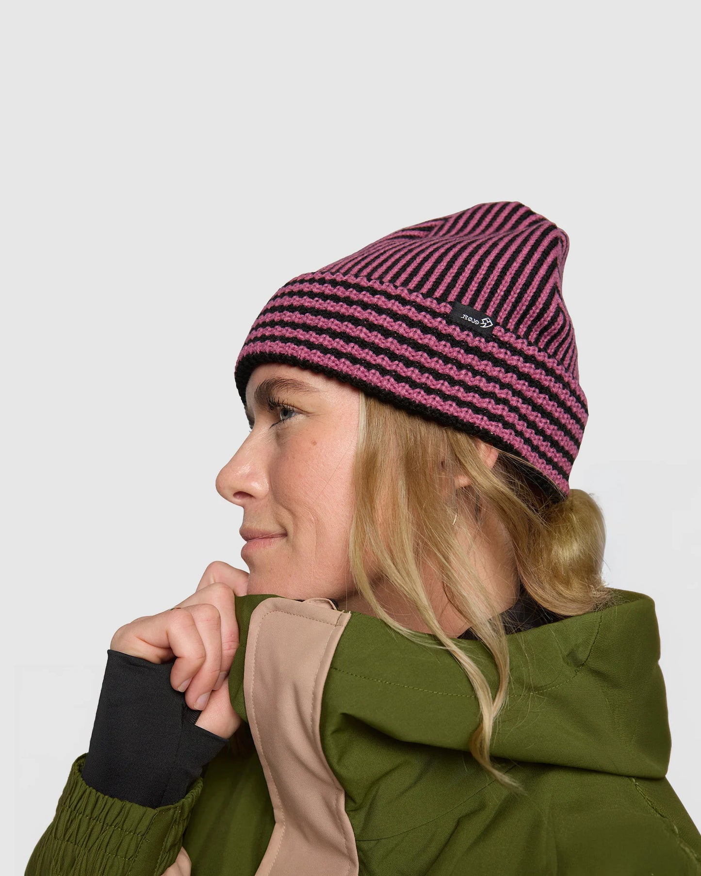 Rojo Vert Beanie  Person wearing a striped beanie and green jacket on a plain background
