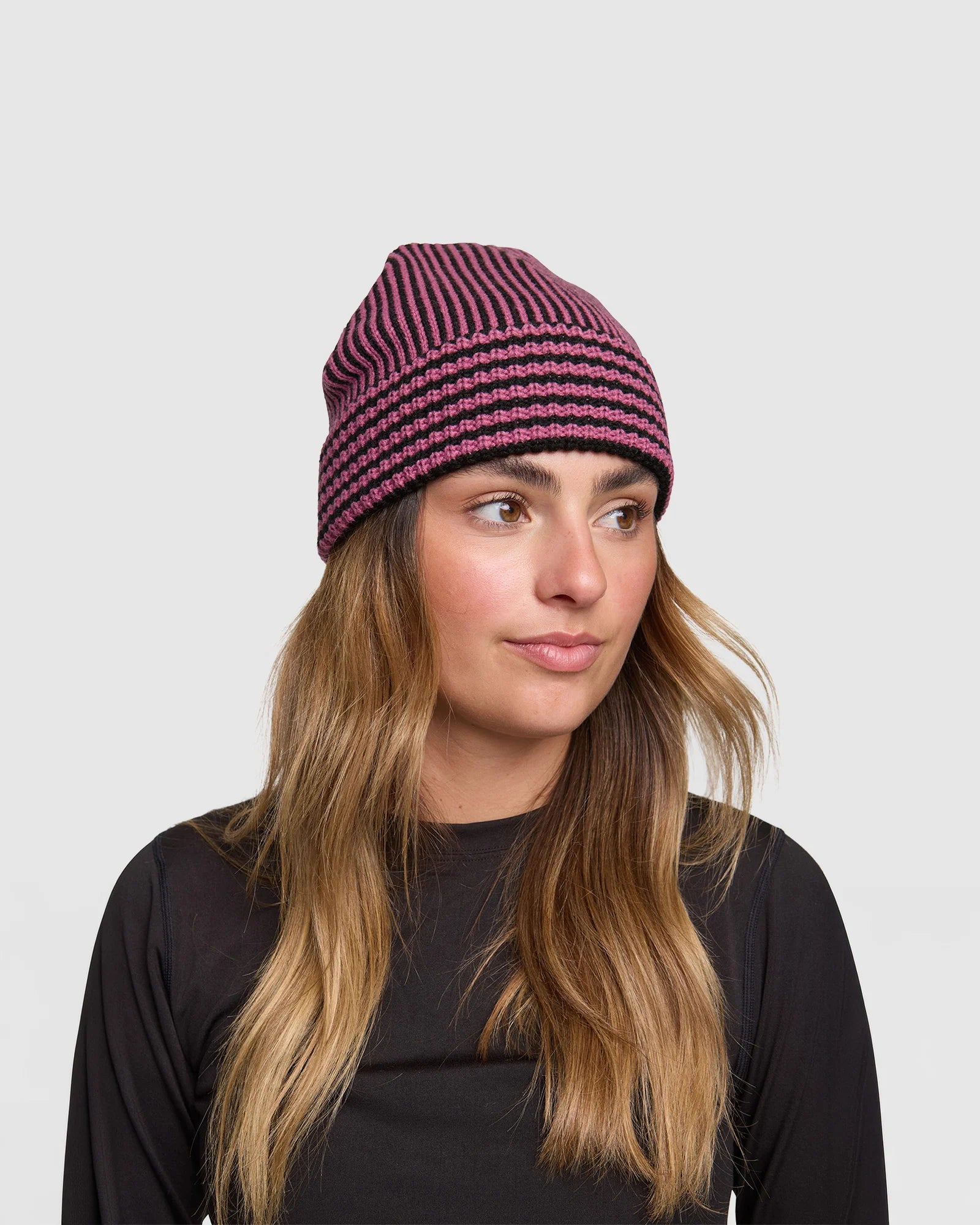 Rojo Vert Beanie  Woman wearing a striped beanie against a plain background