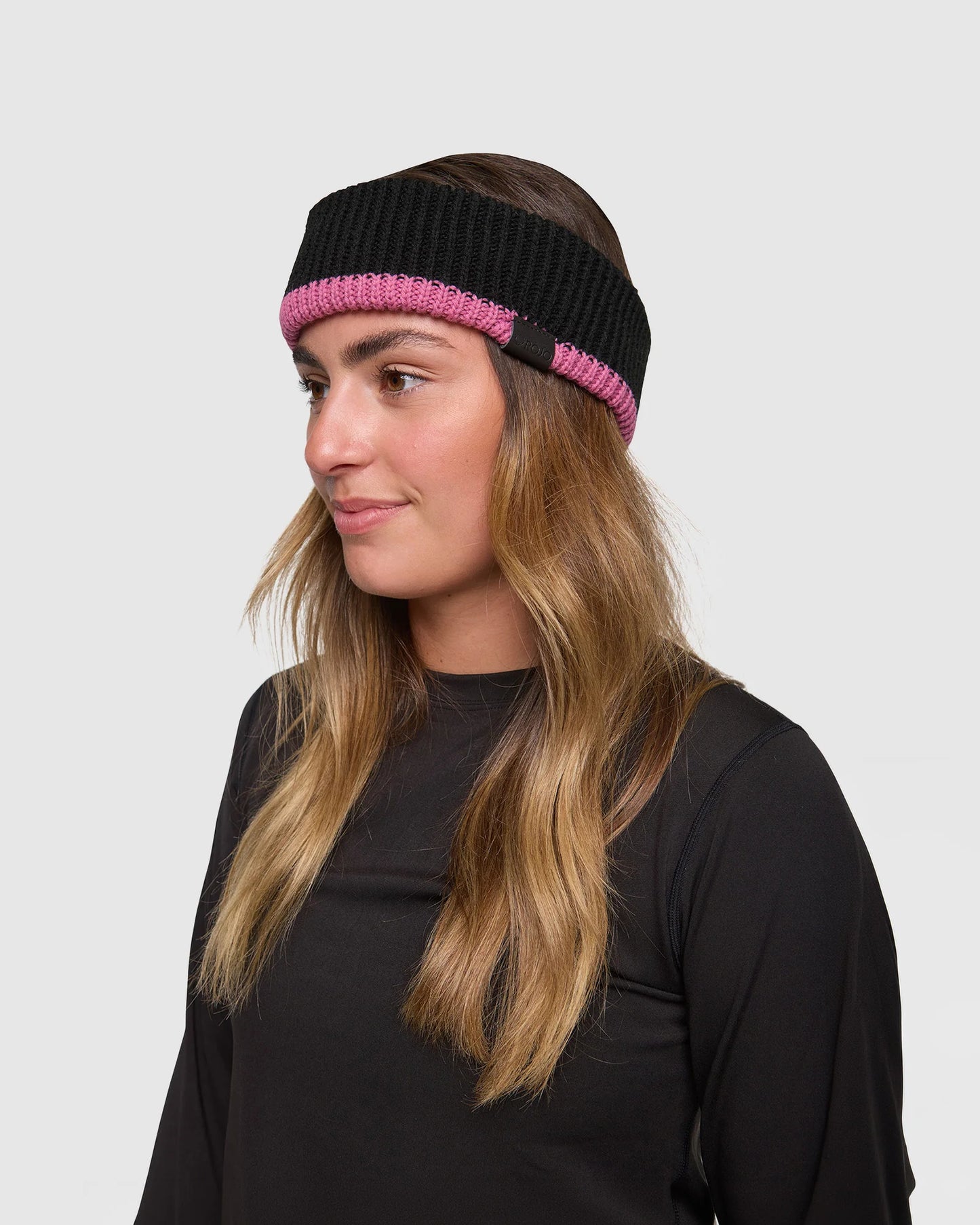 Rojo Chunky Headband Woman wearing a black and pink knit headband on a white background