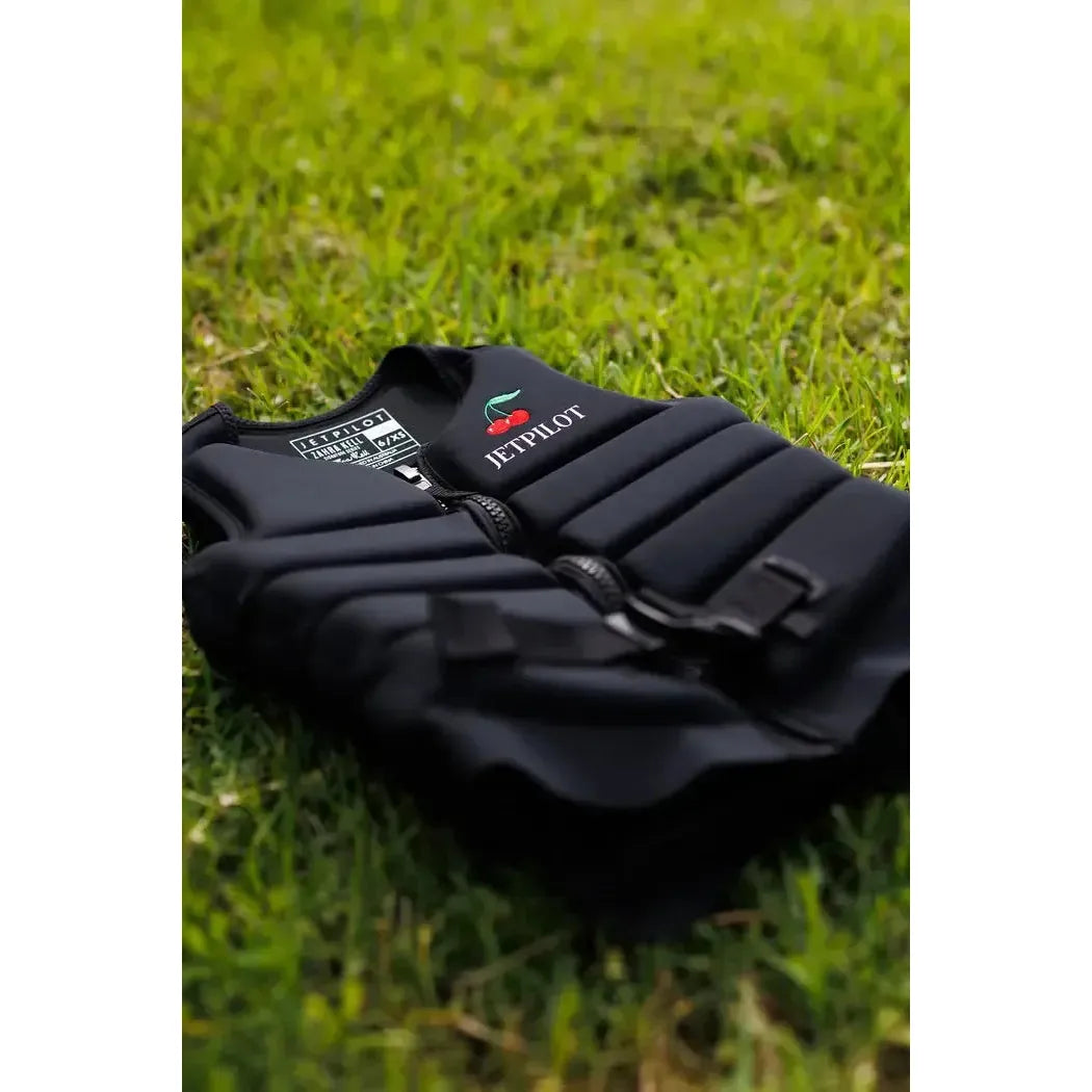 Black Jetpilot wakeboard vest with cherry logo on grass, water sports safety gear