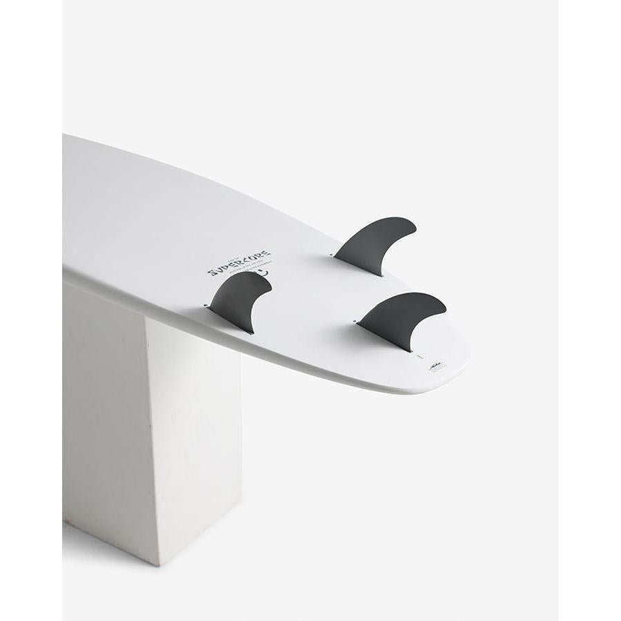 White surfboard with black fins on display against a white background