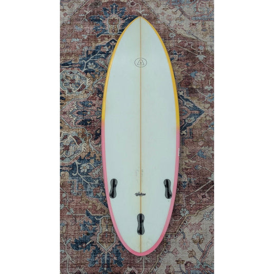 Surfboard with a pink accent on a patterned rug