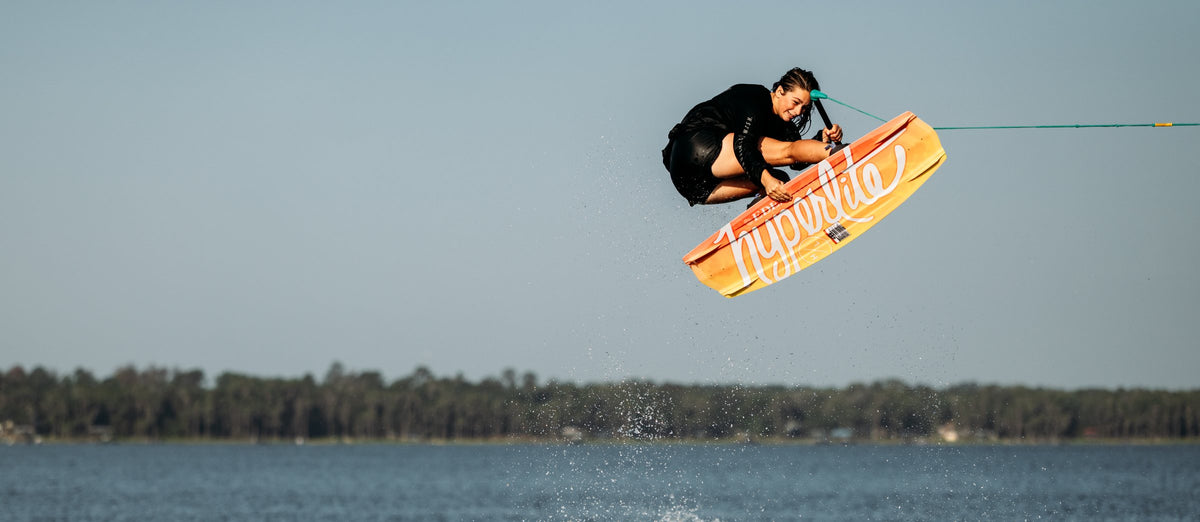 Rider boosting a big air on an orange 2027 Hyperlite wakeboard